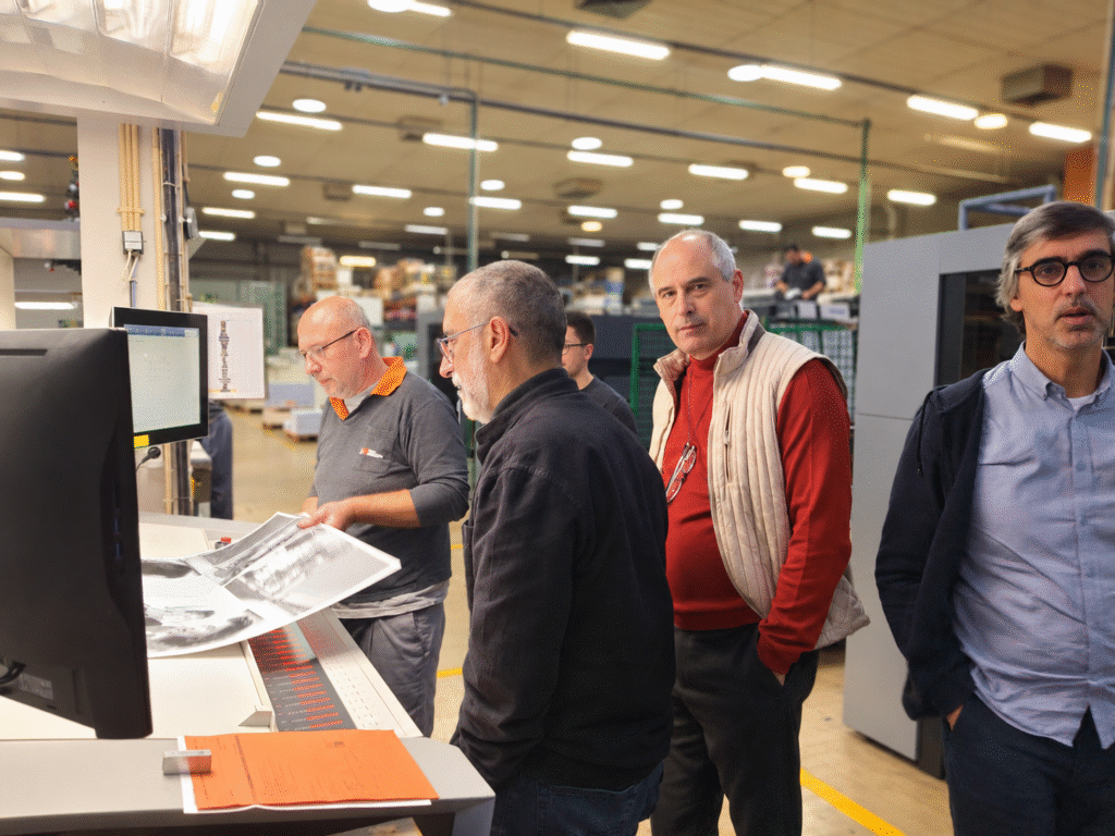 Visita à fábrica com equipa e clientes junto de equipamento industrial de produção